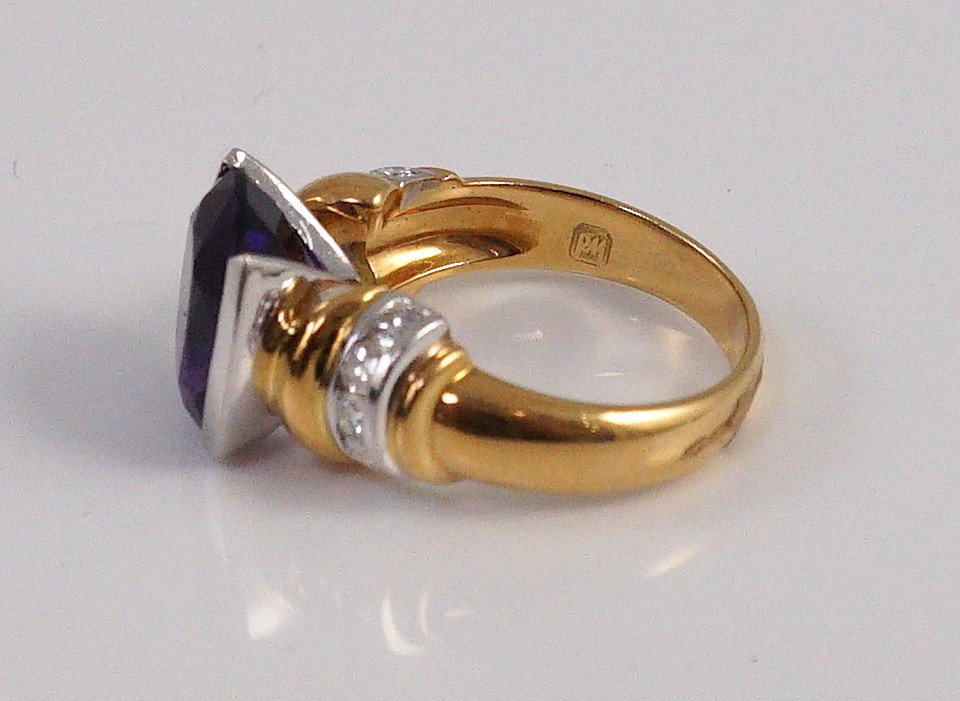 A modern 18ct gold and single stone cushion cut amethyst set dress ring, with ten stone diamond set shoulders